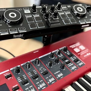 Könnte beinhalten: Ein schwarzer Hercules DJ-Controller mit einem Jogwheel und Knöpfen ist auf einem roten Nord Stage 3 Keyboard montiert.