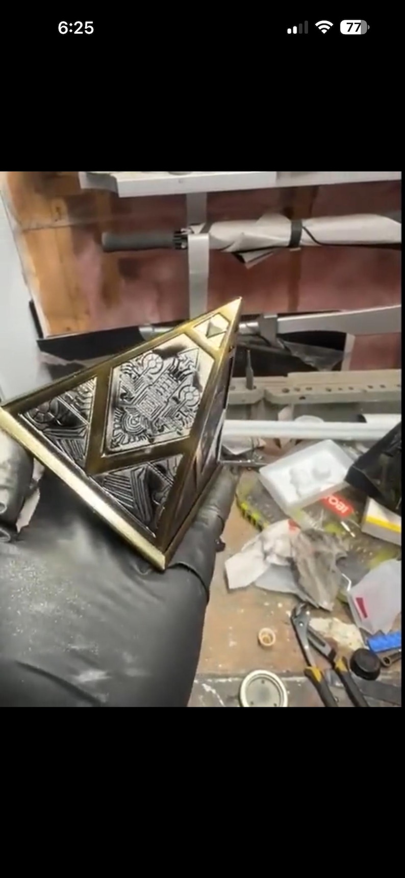 May include: A metallic, geometric object with intricate engraved patterns. The object has a gold-coloured trim and a silver-coloured centre. The design appears to be a decorative piece or a component of a larger structure.