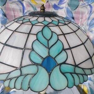 May include: A stained glass lampshade with a blue and green floral design. The lampshade is made of glass and has a metal frame.