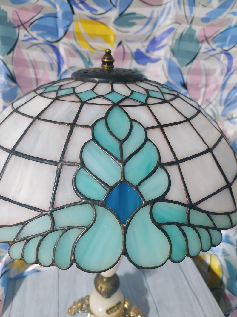 May include: A stained glass lampshade with a blue and green floral design. The lampshade is made of glass and has a metal frame.