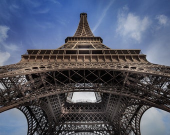 May include: A low angle view of the Eiffel Tower in Paris, France. The tower is made of metal and has a lattice design. The sky is blue and there are some clouds in the sky.