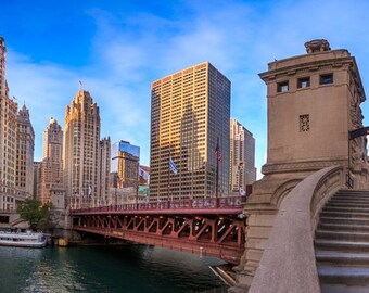May include: A panoramic view of a city skyline with a bridge and a set of stairs leading up to a building. The bridge is red and the building is made of stone. The city skyline is in the background and the sky is blue.