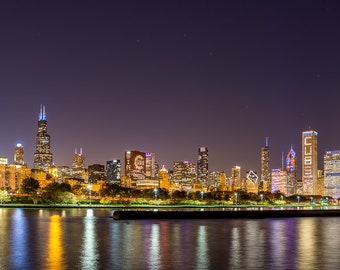 May include: A night view of the Chicago skyline with the word "CUBS" illuminated on a building. The city lights are reflected in the water.