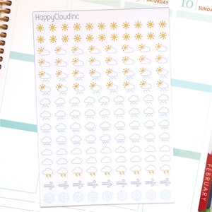 May include: A sheet of weather stickers featuring a variety of weather icons, including sunshine, clouds, rain, lightning, wind, and snowflakes. The stickers are white with gold, blue, and grey accents. The sheet is labelled "HappyCloudinc".