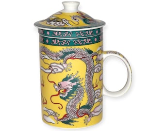 Puede incluir: Taza de cerámica amarilla con tapa, con un diseño detallado de dragón en verde, rosa y blanco. La taza tiene un asa blanca y una banda decorativa verde y blanca. El dragón está sobre un fondo amarillo.