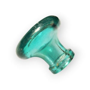 May include: A teal-colored glass cabinet knob with a rounded top and a short, cylindrical base. The knob has a slightly aged appearance, with some imperfections and variations in the glass. The knob is designed for use on a cabinet or drawer.
