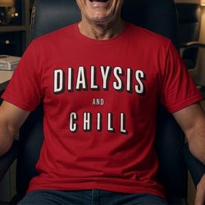 May include: A bright red short-sleeved t-shirt featuring the text DIALYSIS AND CHILL printed in bold white capital letters with a black drop shadow effect. The word DIALYSIS is arched at the top, followed by AND, and CHILL at the bottom.
