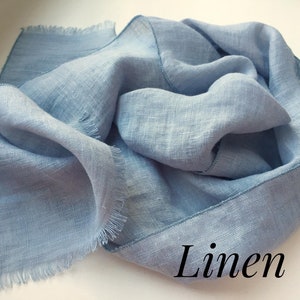 May include: A light blue linen scarf with frayed edges. The scarf is folded and has a subtle texture. The word "Linen" is written in black text at the bottom of the image.