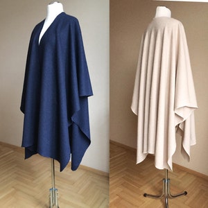 May include: Two different colored ponchos displayed on mannequins. The poncho on the left is navy blue and the poncho on the right is beige.