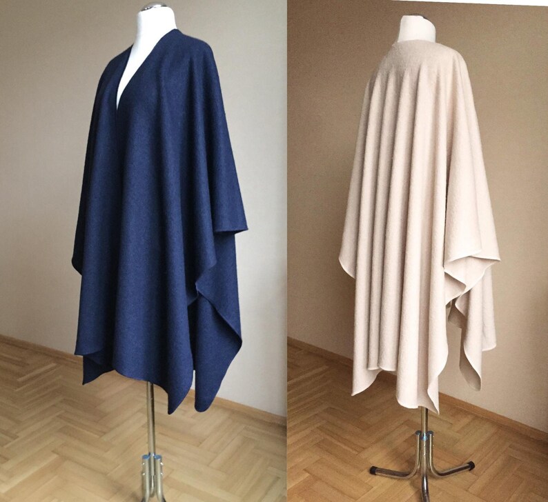 May include: Two different colored ponchos displayed on mannequins. The poncho on the left is navy blue and the poncho on the right is beige.