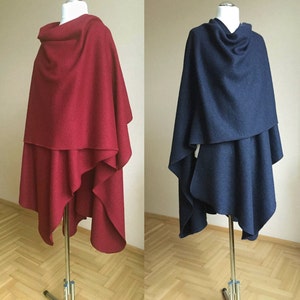 May include: Two draped wool ponchos, one in a deep red and the other in a dark navy blue. Both ponchos have a cowl neck and are styled with a loose, asymmetrical drape.