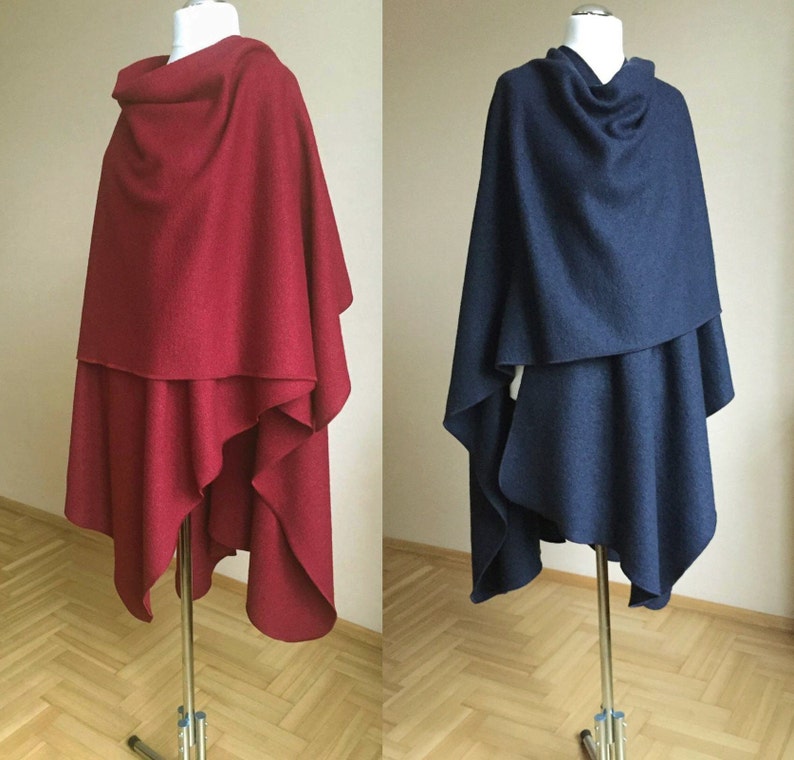 May include: Two draped wool ponchos, one in a deep red and the other in a dark navy blue. Both ponchos have a cowl neck and are styled with a loose, asymmetrical drape.