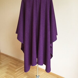 May include: A purple wool poncho draped over a mannequin. The poncho is a simple design with no embellishments.
