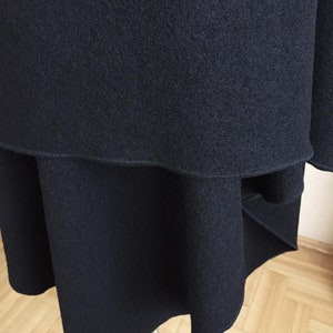 May include: A black skirt with a layered design and a slightly uneven hemline. The skirt is made of a soft, textured fabric.