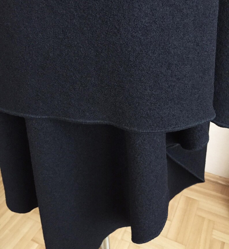 May include: A black skirt with a layered design and a slightly uneven hemline. The skirt is made of a soft, textured fabric.