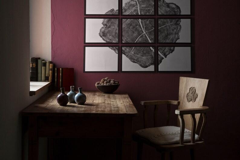 May include: A wooden table with a dark brown finish sits in a room with a burgundy wall. A chair with a carved wooden back and a white cushion sits next to the table. Three small ceramic vases sit on the table, and a bowl of dried berries sits on the table in front of the chair.