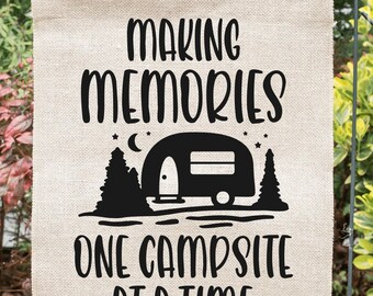 May include: A burlap garden flag with black text that reads "Making Memories One Campsite At A Time". A black silhouette of a camper and trees is in the center of the flag.