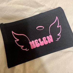 May include: Black canvas zippered pouch with pink angel wings and a halo above the name "HELEN" in pink.