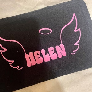 May include: Black canvas zippered pouch with pink angel wings and a halo, and the name "HELEN" in pink letters.