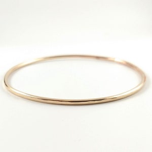 May include: A simple gold bangle bracelet with a hammered finish.