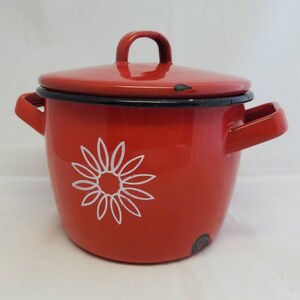 May include: Red enamel pot with a white daisy design and a black rim. The pot has a lid and two handles.