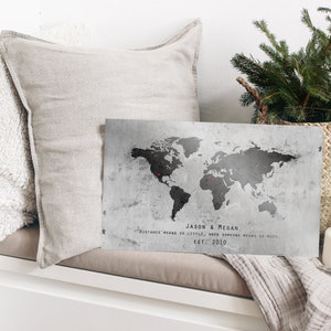 May include: A gray and black world map print with two red pins marking locations. The print has the text "Jason & Megan" and "Distance means so little, when someone means so much. Est. 2010".