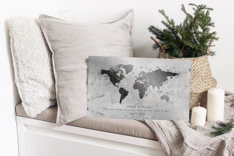 May include: A gray and black world map print with two red pins marking locations. The print has the text "Jason & Megan" and "Distance means so little, when someone means so much. Est. 2010".