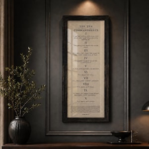 Puede incluir: Una pieza de arte mural rectangular vertical que presenta los Diez Mandamientos impresos en texto negro sobre un fondo beige claro. La impresión está encerrada en un marco de madera oscura y desgastada con veta visible, mostrando el texto completo.