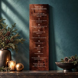 May include: A tall, rectangular wall plaque with a dark, weathered copper-toned finish featuring the text of The Ten Commandments in white lettering, numbered I through X, displayed in a vertical orientation on a dark surface.