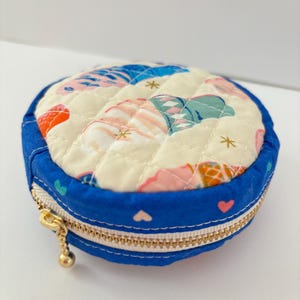 Pochette rotonda in tessuto di cotone, trapuntata e foderata, con cerniera, realizzata a mano.