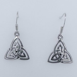 May include: A pair of silver-toned drop earrings featuring a triangular triquetra knot design. Each earring hangs from a simple hook wire and displays an intricate, open-work metal pattern with three interconnected loops forming a central triangle.