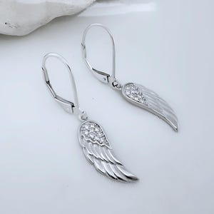 May include: Silver dangle earrings with a wing design and clear cubic zirconia stones.