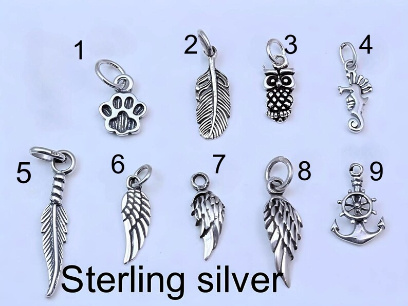May include: A collection of nine sterling silver charms numbered one through nine, featuring designs including a paw print, feathers, an owl, a seahorse, wings, and an anchor with a ship wheel. Each charm includes a small jump ring for attachment.