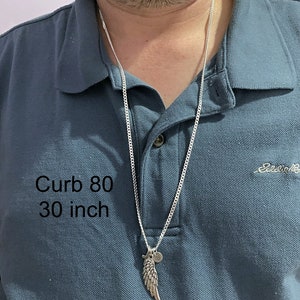 May include: A silver curb chain necklace with a silver wing pendant and a small round charm. The chain is 30 inches long and is labeled "Curb 80".