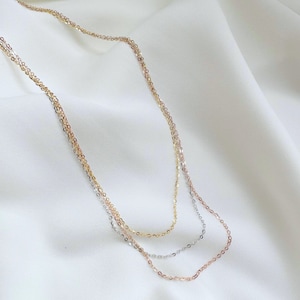 Puede incluir: Un collar de capas con tres cadenas en oro, plata y oro rosa.