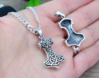 May include: A silver Mjolnir pendant necklace with a detailed knotwork design. The pendant is shown from the front and back, revealing the intricate details of the design.