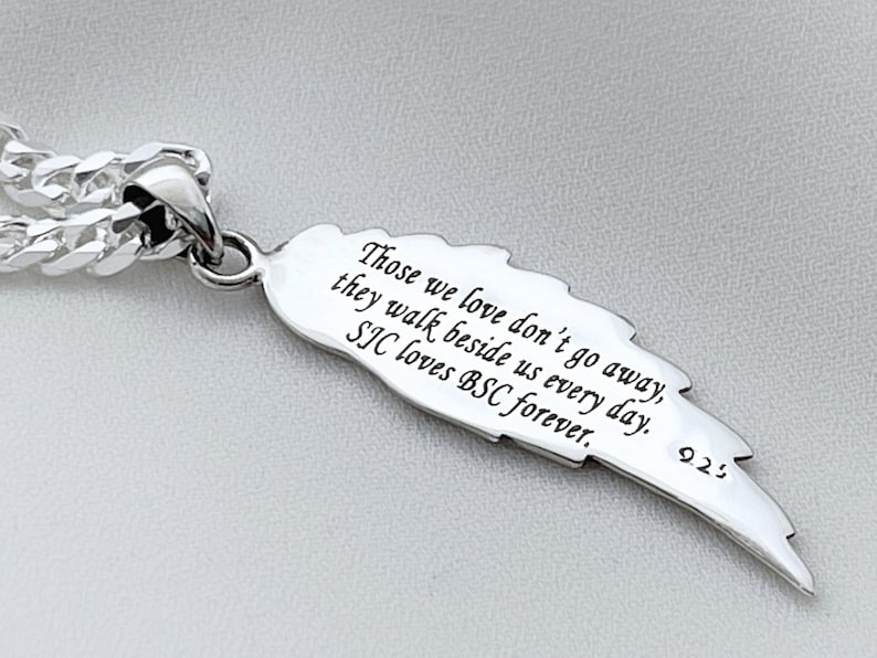 May include: Silver pendant necklace with a feather charm. The feather has an inscription that reads: "Those we love don't go away, they walk beside us every day. SIC loves BSC forever." The pendant is attached to a silver curb chain.