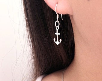 Könnte beinhalten: Ein silberfarbener Metallohrring mit einem kleinen Ankeranhänger, der an einem einfachen Haken befestigt ist. Das Ankerdesign ist schlicht und metallisch und hängt vertikal an einem kleinen runden Glied, das mit dem Ohrhaken verbunden ist.