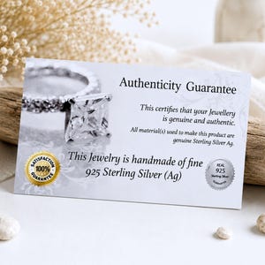 Puede incluir: Una tarjeta de garant&iacute;a de autenticidad rectangular blanca con una fotograf&iacute;a de un anillo con piedra cuadrada. El texto dice Authenticity Guarantee, This certifies that your Jewellery is genuine and authentic, y This Jewelry is handmade of fine 925 Sterling Silver (Ag).