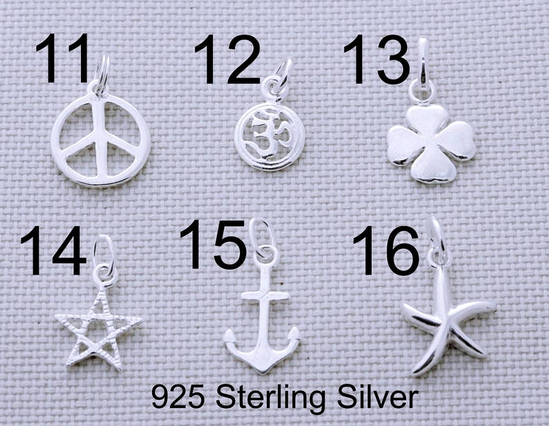 Puede incluir: Seis dijes de plata numerados del 11 al 16, que incluyen un s&iacute;mbolo de paz, un s&iacute;mbolo Om, un tr&eacute;bol de cuatro hojas, una estrella, un ancla y una estrella de mar. Cada dije tiene una argolla. El texto 925 Sterling Silver aparece abajo.