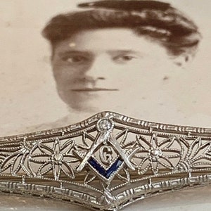 May include: A silver filigree brooch with a blue enamel Masonic symbol and a single diamond in the center.