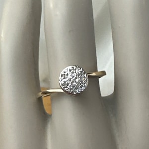 May include: A silver ring with a round, pave-set diamond center stone.