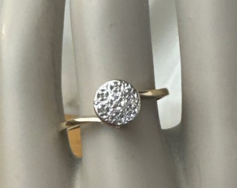 Puede incluir: Un anillo de plata con una piedra central redonda de diamantes pavé.