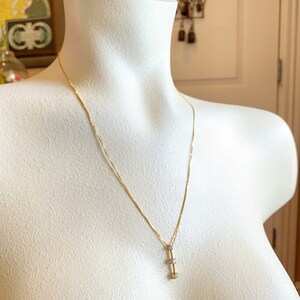 May include: A gold chain necklace with a pendant featuring three small, clear gemstones arranged vertically.