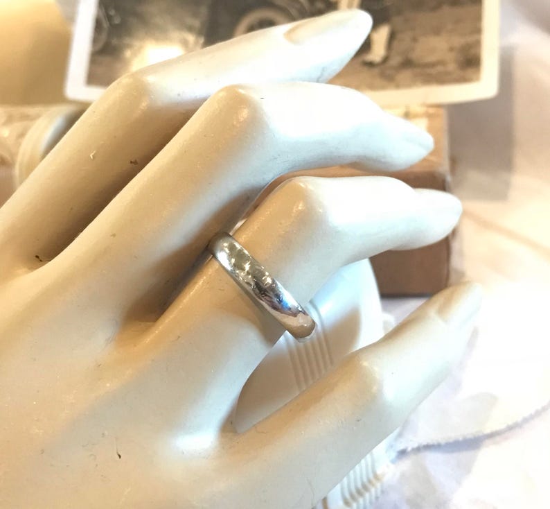 May include: A simple silver wedding band with a smooth, slightly rounded surface.