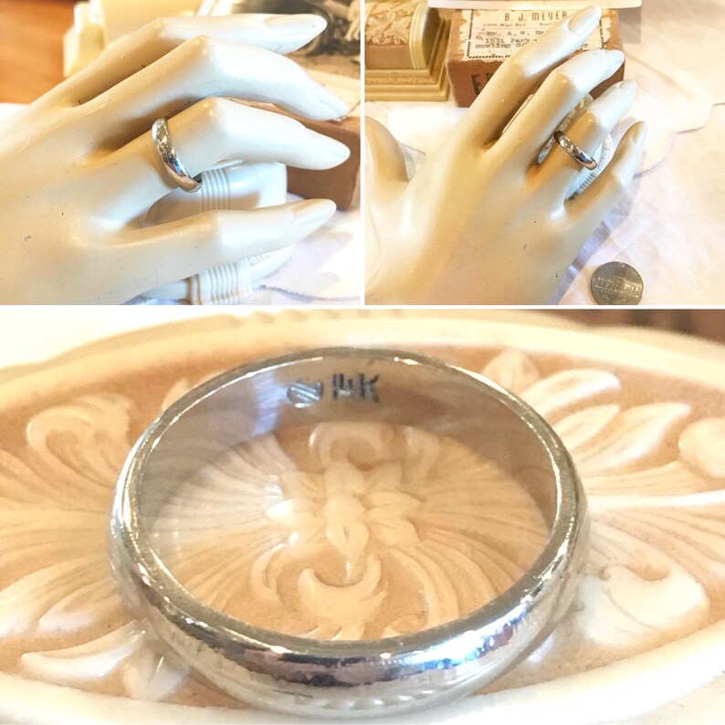 May include: A silver wedding band with a slightly rounded profile and a subtle inscription on the inside of the band. The inscription reads "9 HK".