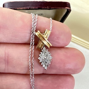 May include: A silver chain necklace with a gold and silver pendant featuring a diamond cluster and a criss-cross design.