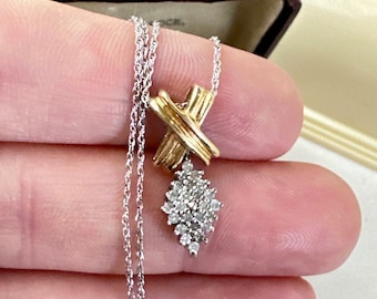 Puede incluir: Un collar de cadena de plata con un colgante de oro y plata con un racimo de diamantes y un diseño de cruz.