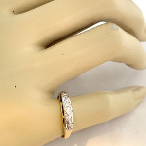 May include: A delicate gold band ring with a diamond-shaped design and a single diamond accent.