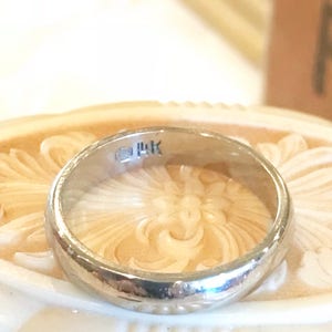 May include: A silver wedding band with a 14K marking on the inside of the band.